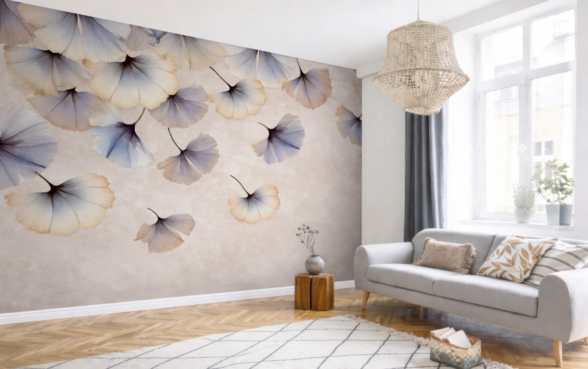 Fototapeta Pastelowe niebieskie i beżowe liście miłorzębu z subtelnymi płatkami unoszącymi się w powietrzu na fakturowanym tle.